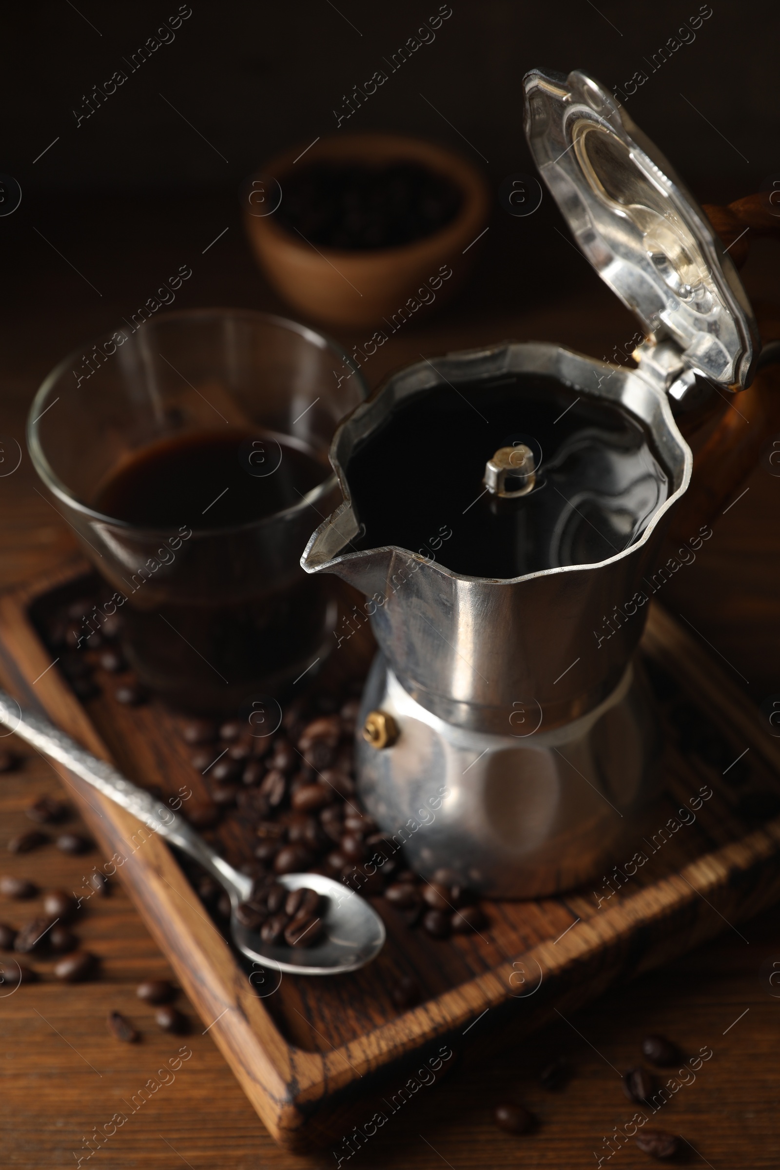 Photo of Brewed coffee, moka pot and beans on wooden table