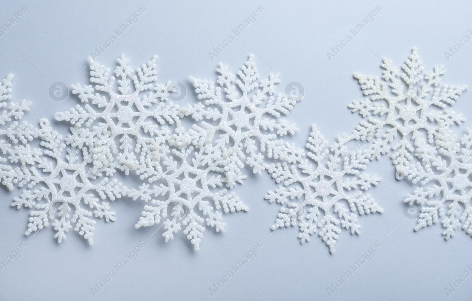 Photo of Beautiful snowflakes on white background, flat lay