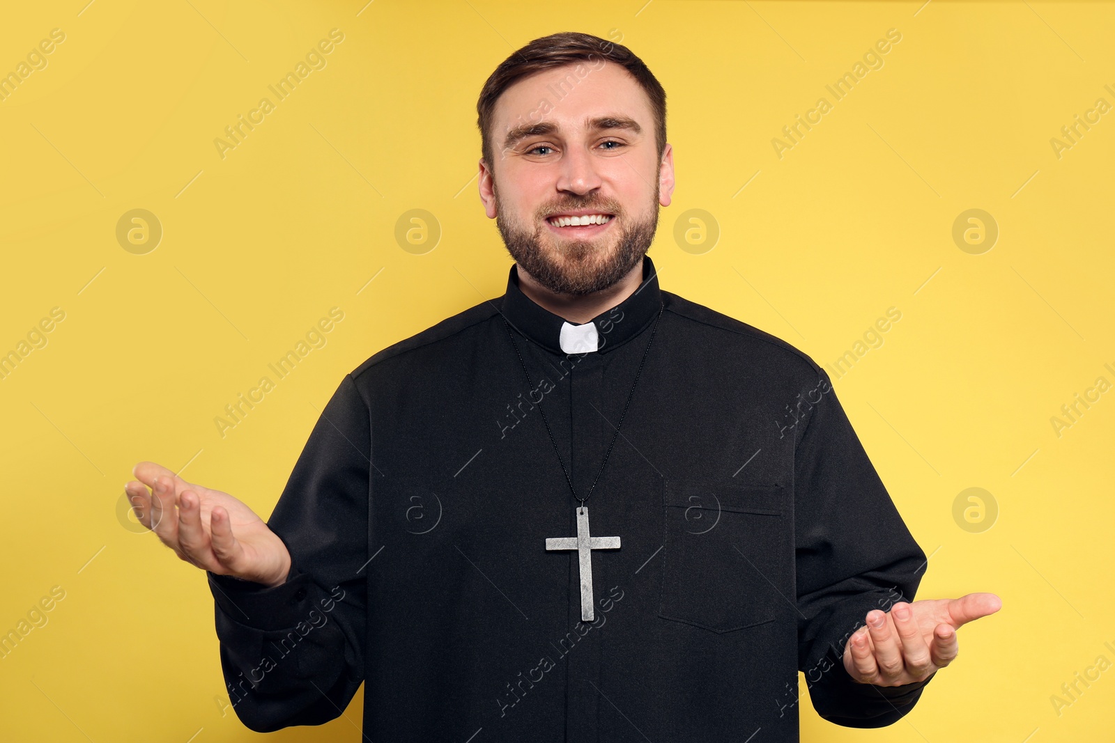 Photo of Priest wearing cassock with clerical collar on yellow background
