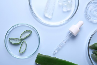 Photo of Flat lay composition with cut aloe vera and cosmetic gel on light blue background