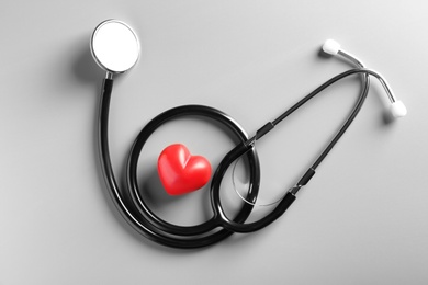 Photo of Stethoscope and small red heart on gray background. Heart attack concept