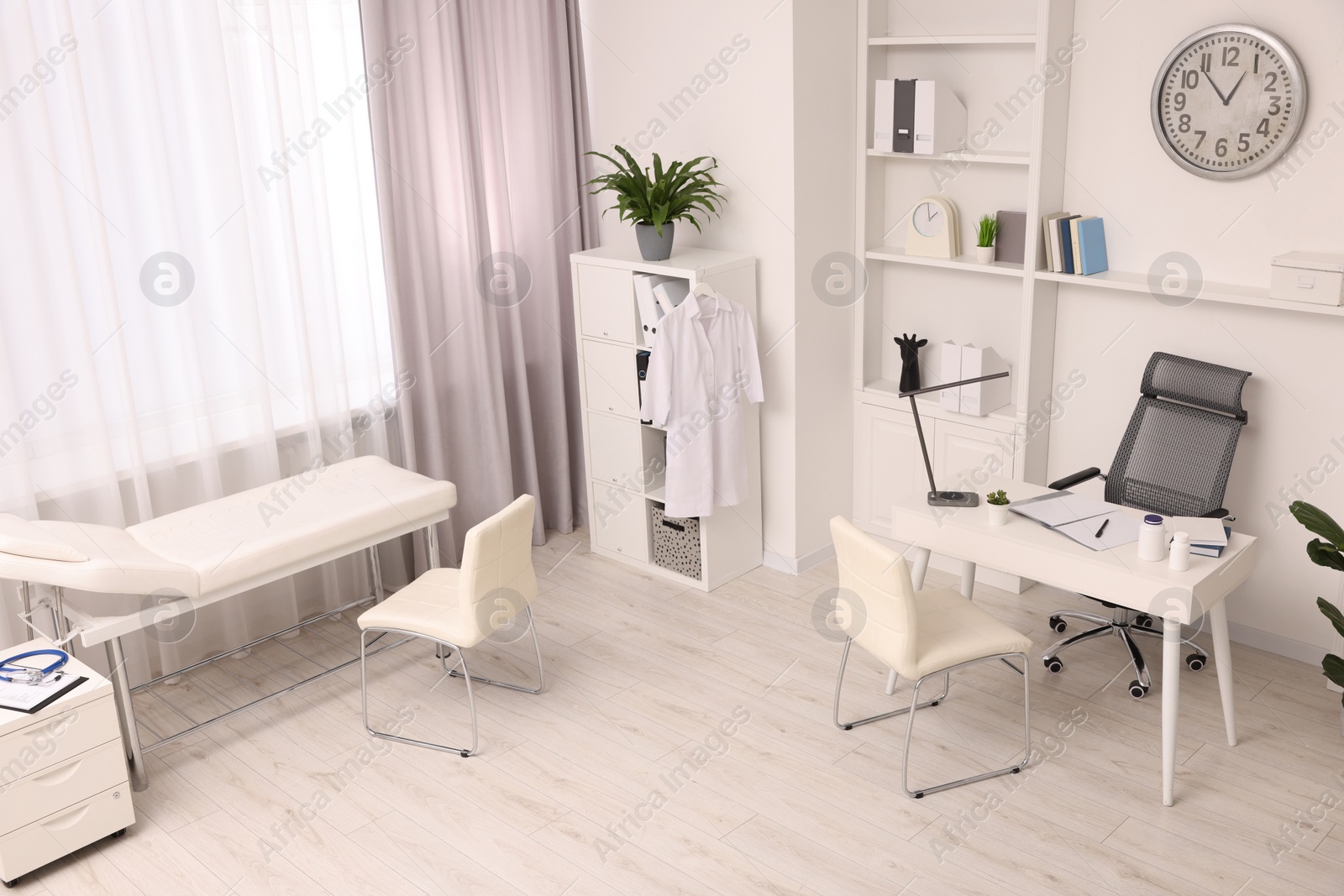 Photo of Modern medical office interior with doctor's workplace and examination table