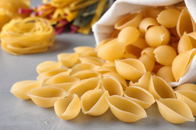 Photo of Uncooked conchiglie pasta on grey table, closeup