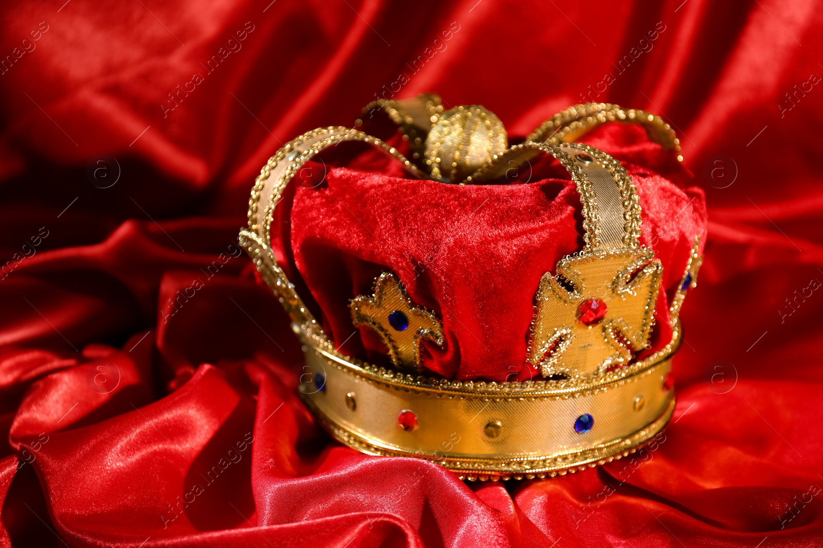 Photo of Beautiful velvet crown on red fabric. Fantasy item