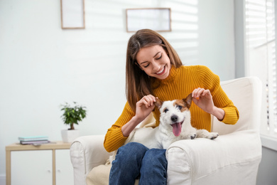 Young woman with her cute Jack Russell Terrier in armchair at home. Lovely pet