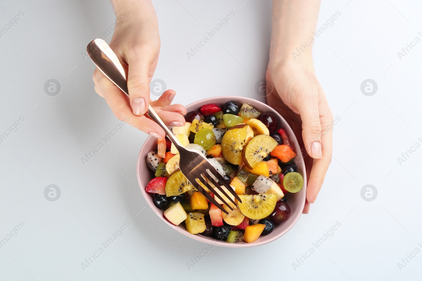 Photo of Woman with delicious exotic fruit salad on white background, top view
