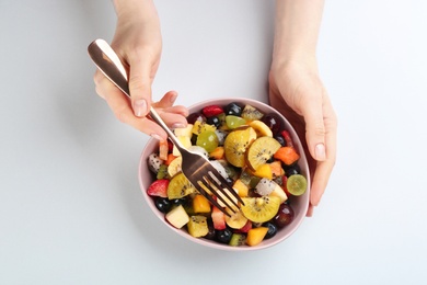 Woman with delicious exotic fruit salad on white background, top view