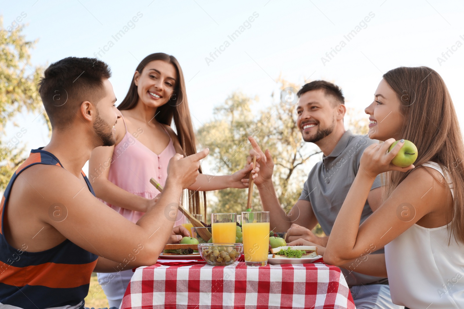 Photo of Happy young people having picnic at table in park