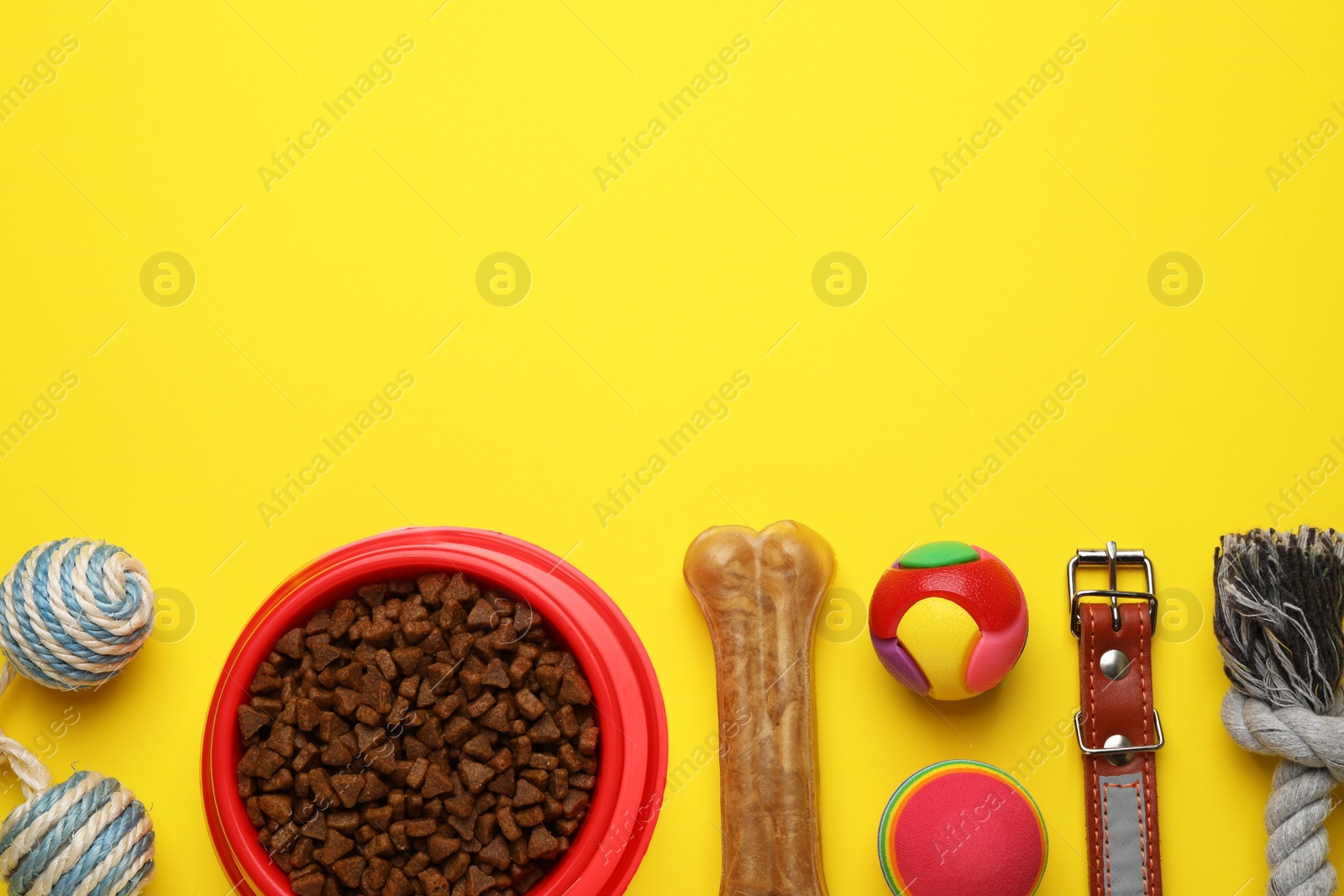 Photo of Flat lay composition with pet toys and feeding bowl on yellow background, space for text