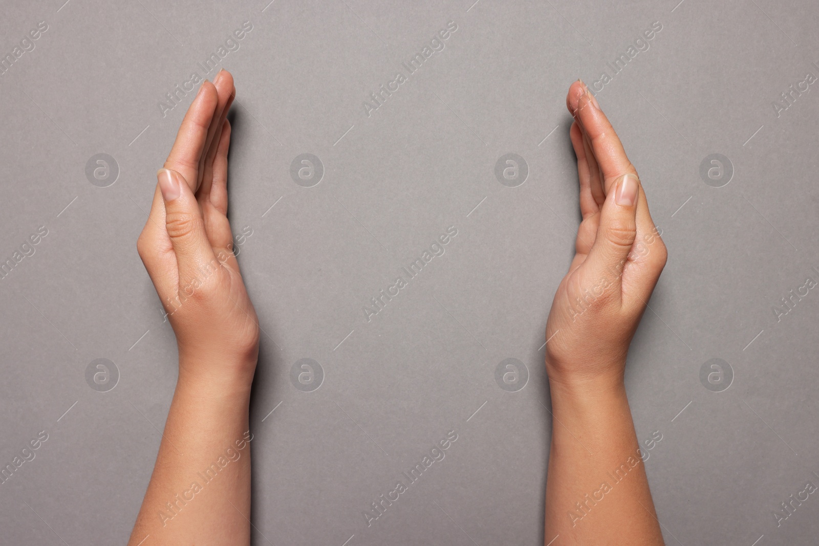 Photo of Woman holding on grey background, closeup of hands. Space for text