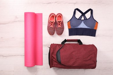 Red bag and sports accessories on floor, flat lay