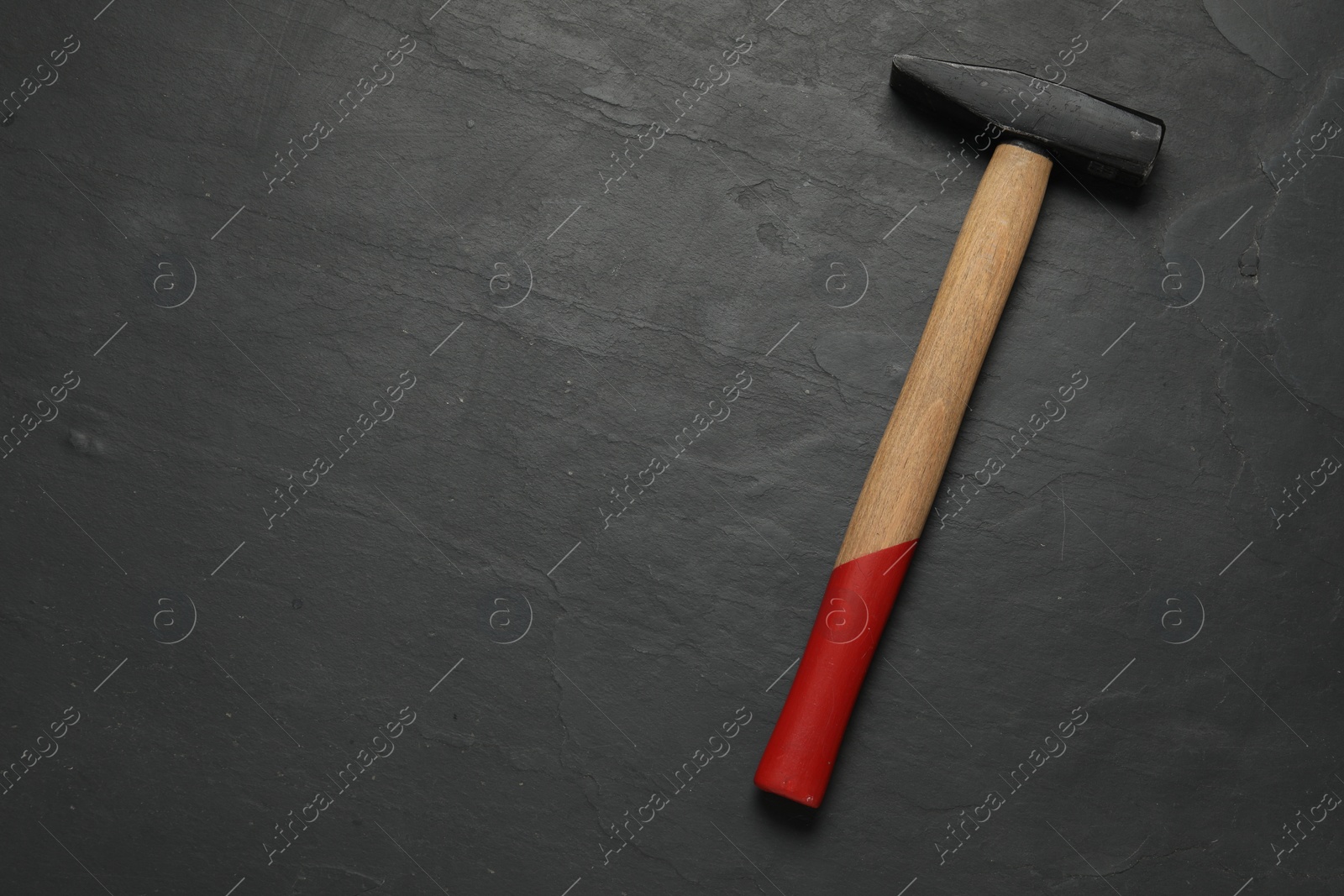 Photo of New hammer on black textured table, top view. Space for text