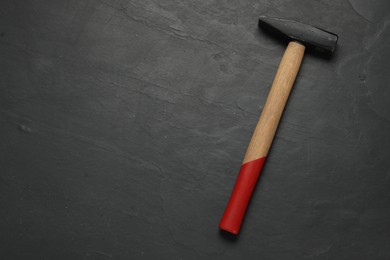 Photo of New hammer on black textured table, top view. Space for text