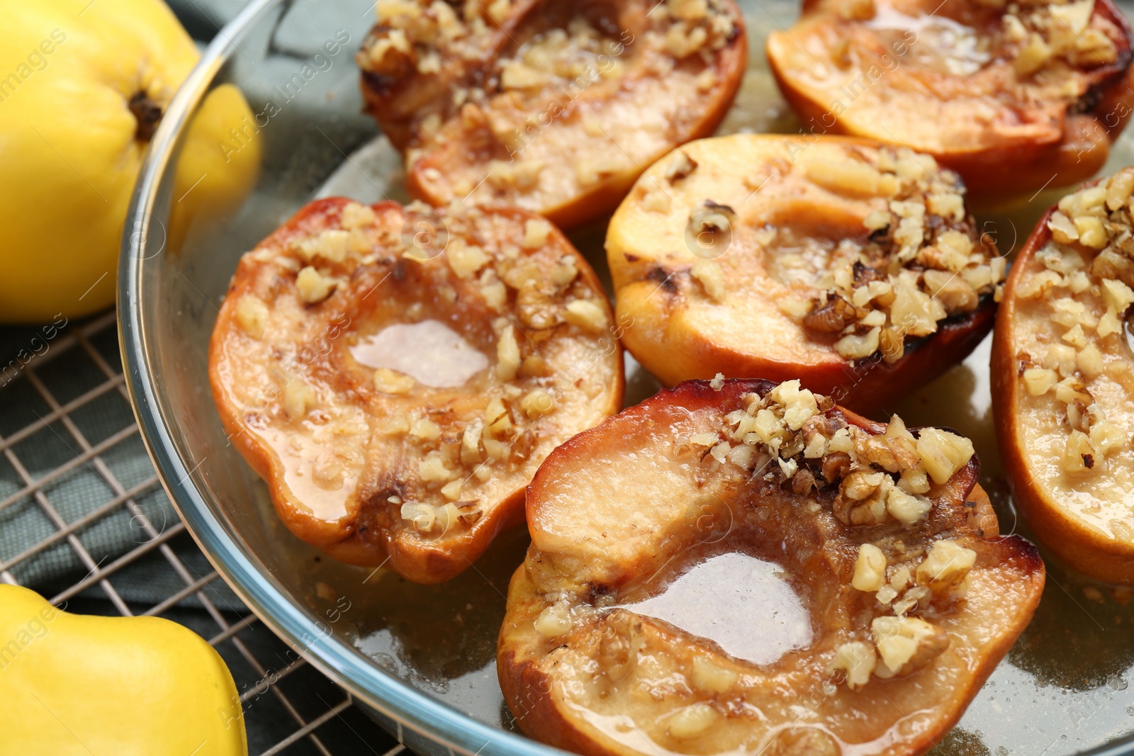 Photo of Tasty baked quinces with walnuts and honey in bowl on table, closeup