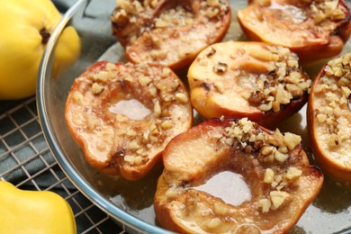 Photo of Tasty baked quinces with walnuts and honey in bowl on table, closeup