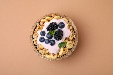 Tasty granola, yogurt and fresh berries in bowl on pale brown background, top view. Healthy breakfast