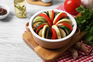 Cooking delicious ratatouille. Dish with different cut vegetables on white wooden table, closeup
