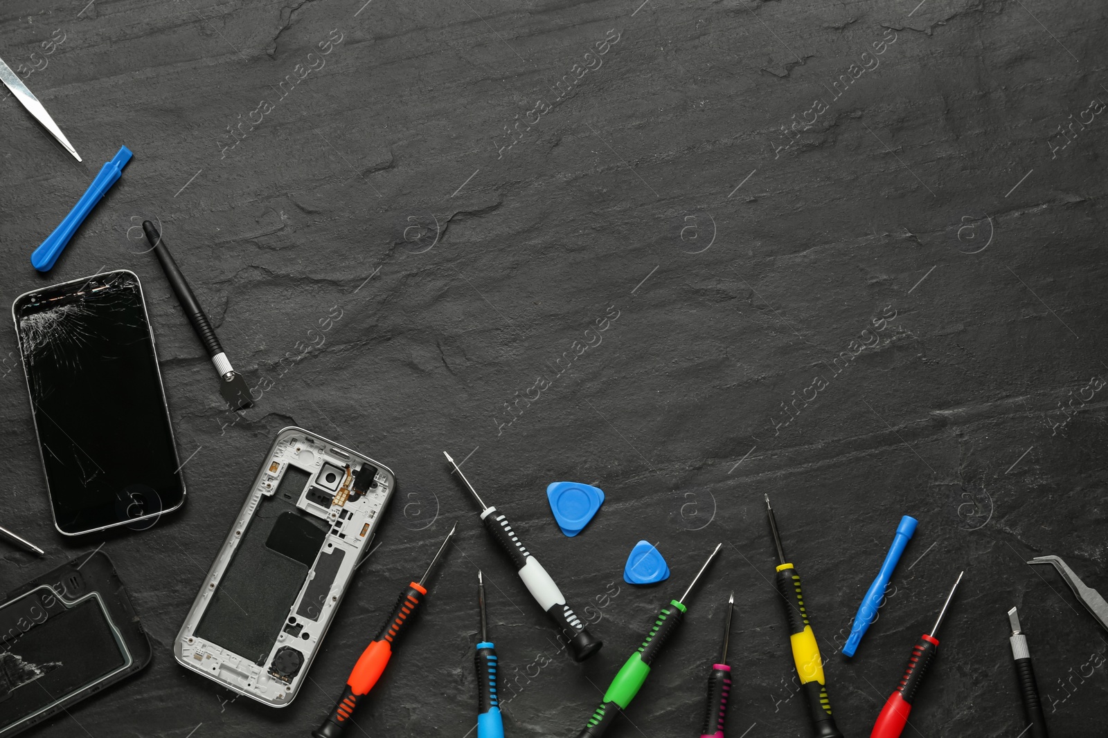 Photo of Damaged smartphone and repair tools on black background, flat lay. Space for text