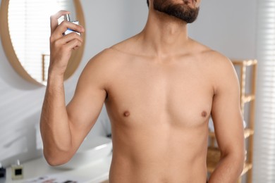 Photo of Young man spraying luxury perfume indoors, closeup