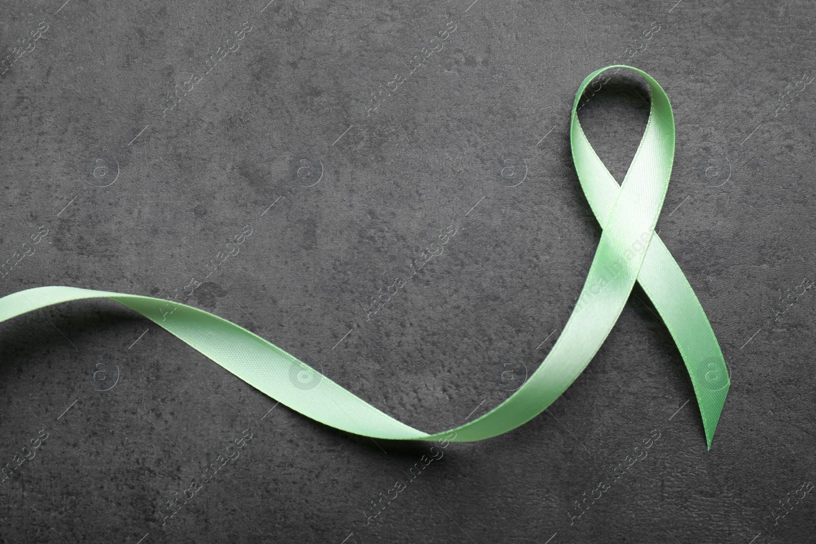 Photo of World Mental Health Day. Green ribbon on black background, top view with space for text