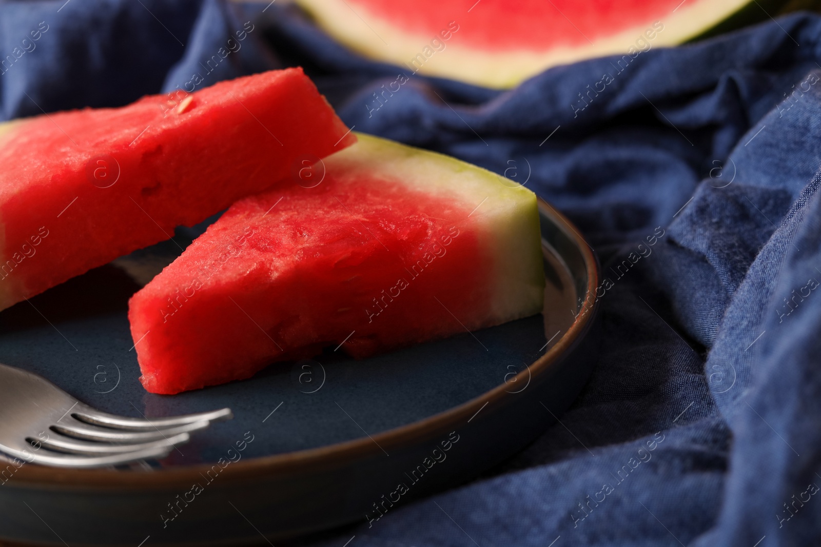 Photo of Sliced fresh juicy watermelon on blue fabric, closeup