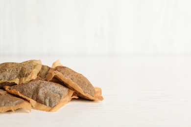 Heap of used tea bags on white wooden table. Space for text