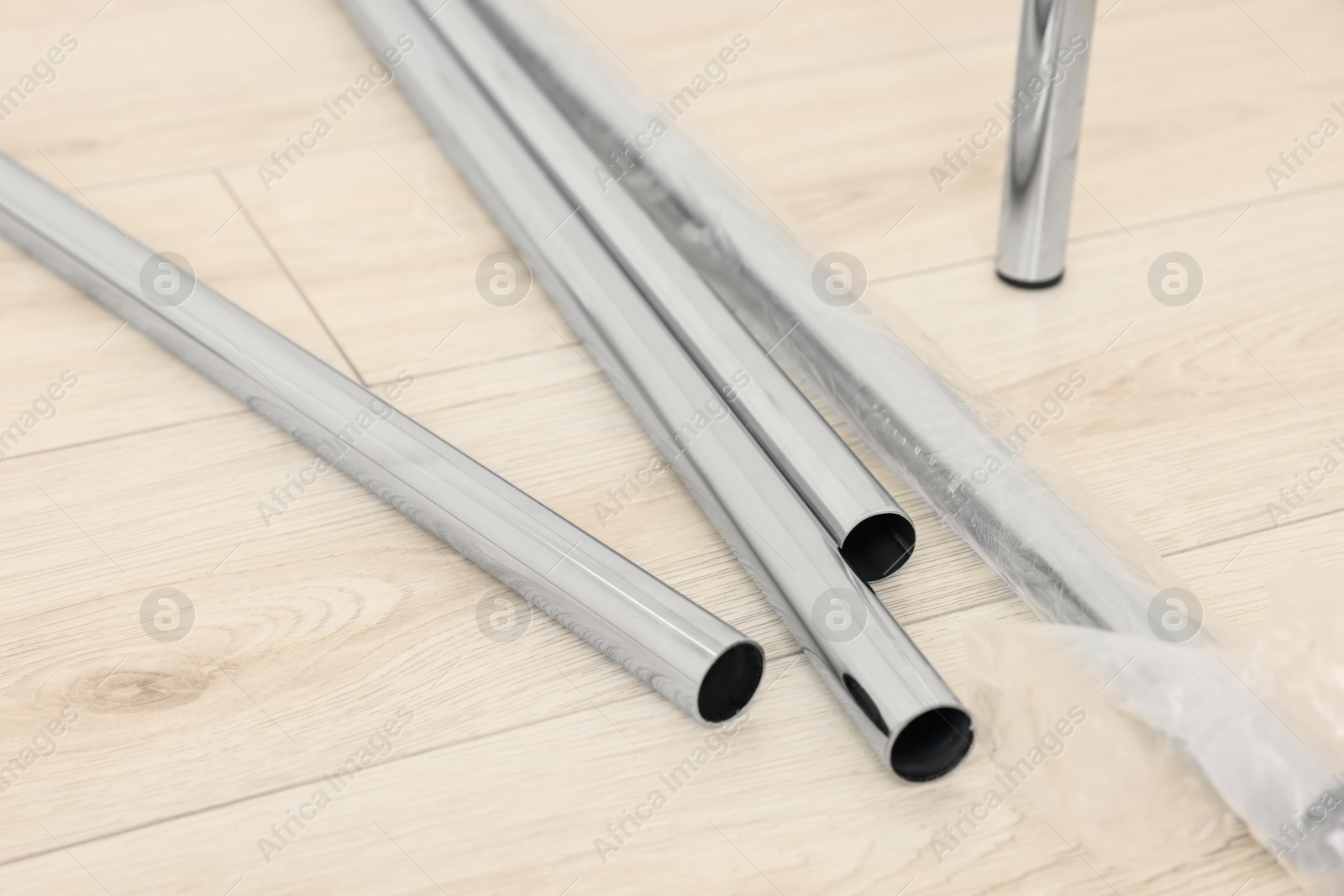 Photo of New modern metal pipes on wooden floor, closeup