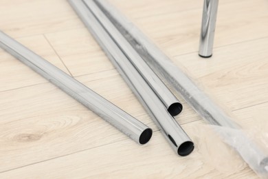 New modern metal pipes on wooden floor, closeup
