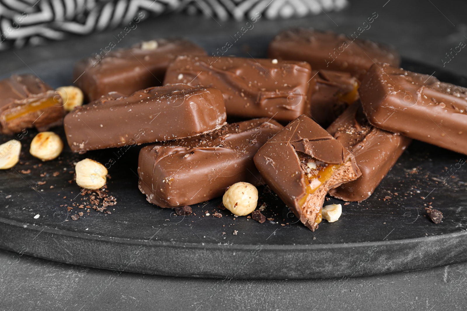 Photo of Delicious chocolate candy bars with caramel and nuts on grey table, closeup