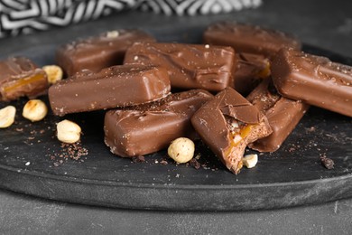 Photo of Delicious chocolate candy bars with caramel and nuts on grey table, closeup