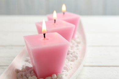 Composition with three burning candles on white table