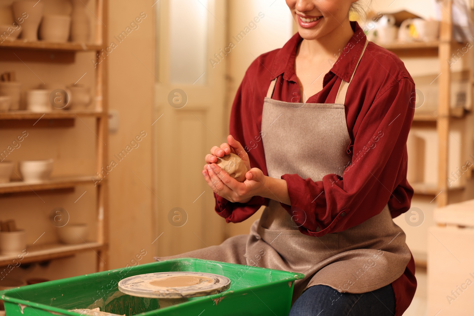 Photo of Woman crafting with clay over potter's wheel indoors, closeup. Space for text