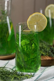 Photo of Glass of refreshing tarragon drink with lemon slice on table