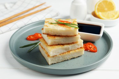 Photo of Delicious turnip cake with chili pepper and green onion on white wooden table