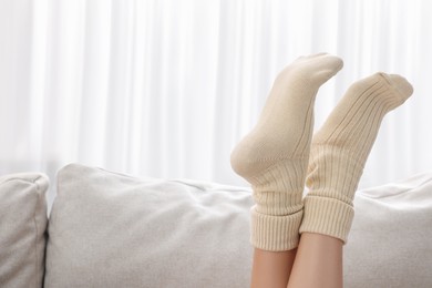 Photo of Woman in warm socks at home, closeup. Space for text
