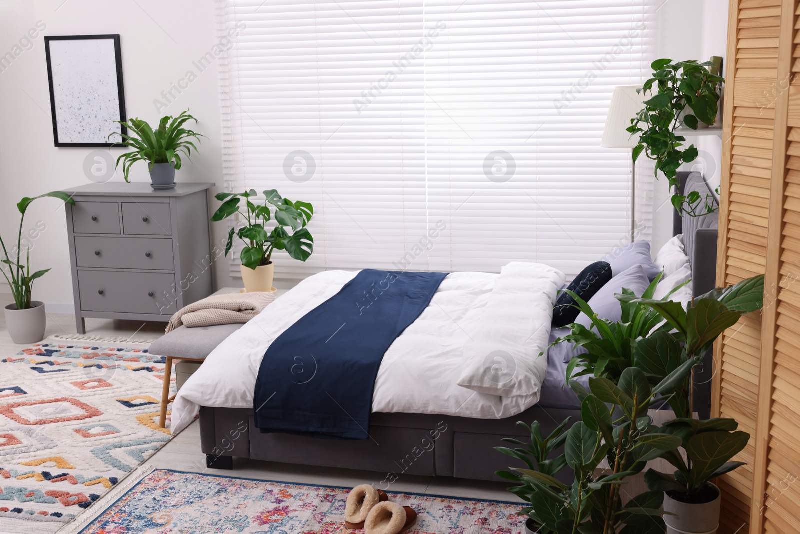 Photo of Stylish bedroom with double bed and beautiful green houseplants. Modern interior