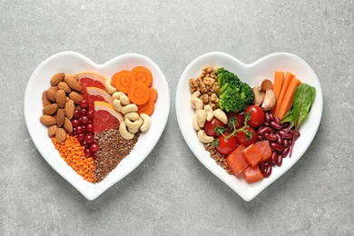 Photo of Plates with products for heart-healthy diet on grey background, top view
