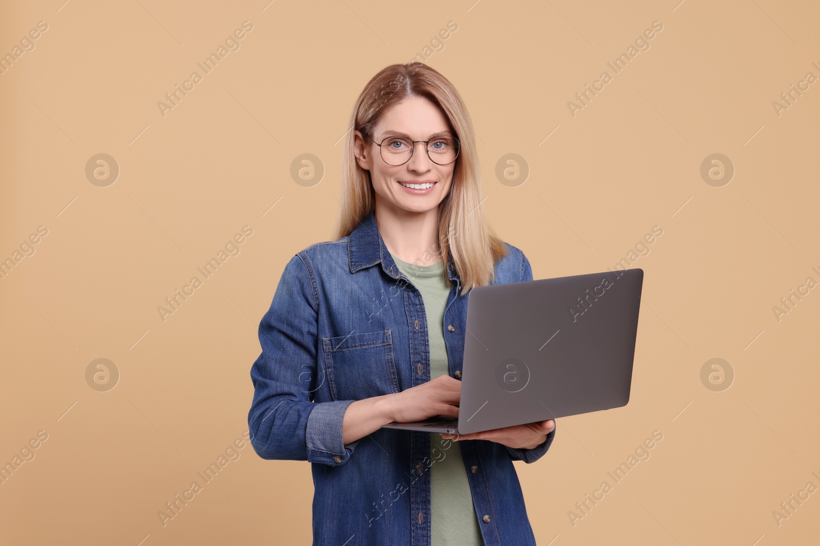 Photo of Happy woman with laptop on beige background