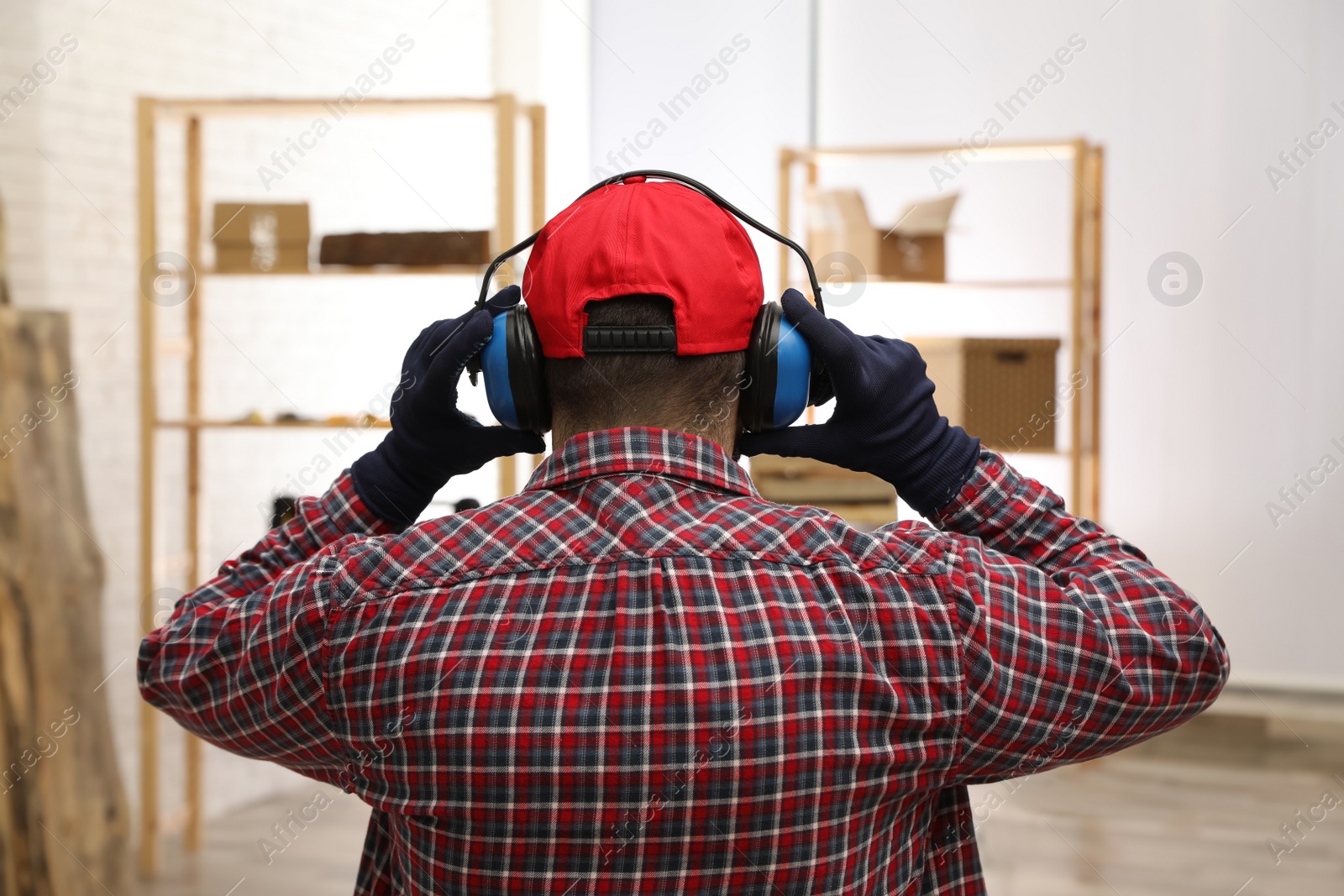 Photo of Worker wearing safety headphones indoors, back view. Hearing protection device