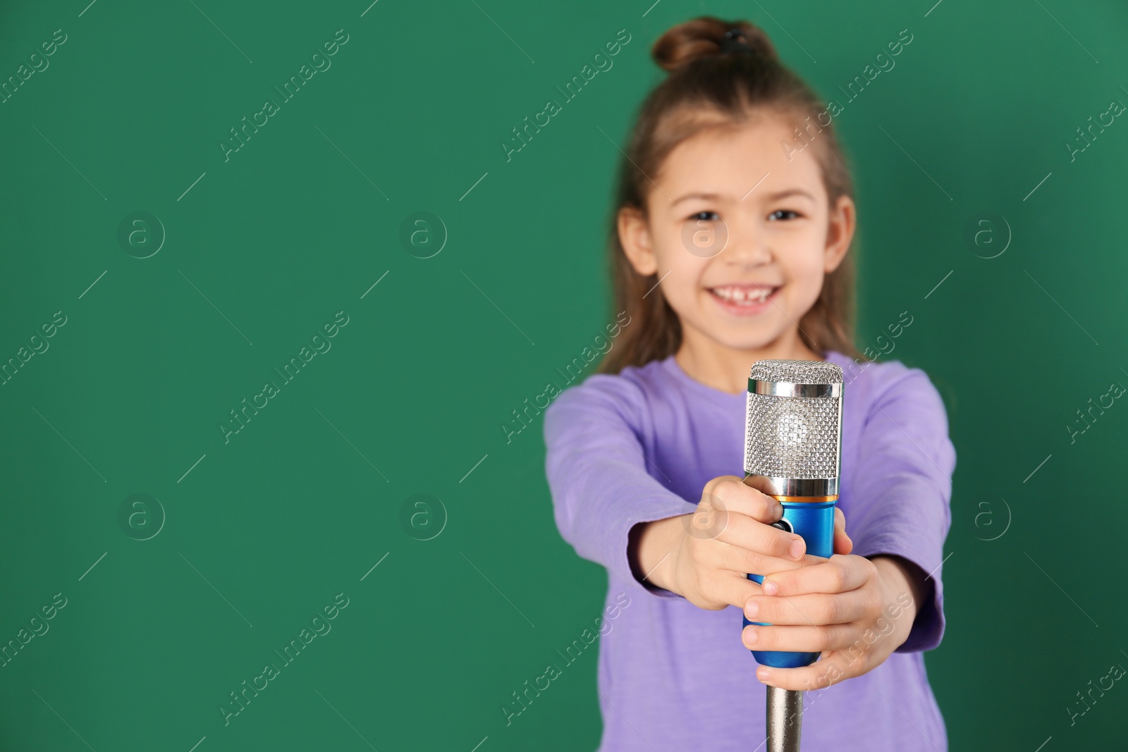 Photo of Cute funny girl with microphone on color background. Space for text