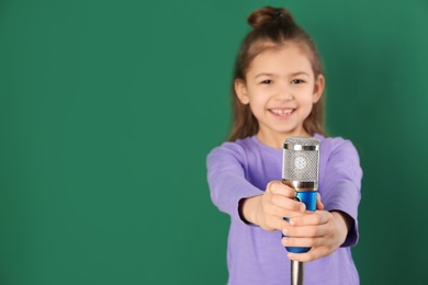 Cute funny girl with microphone on color background. Space for text