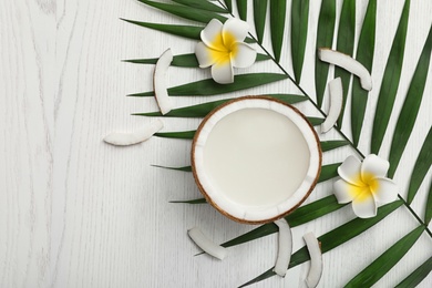 Flat lay composition with half of coconut on white wooden background. Space for text