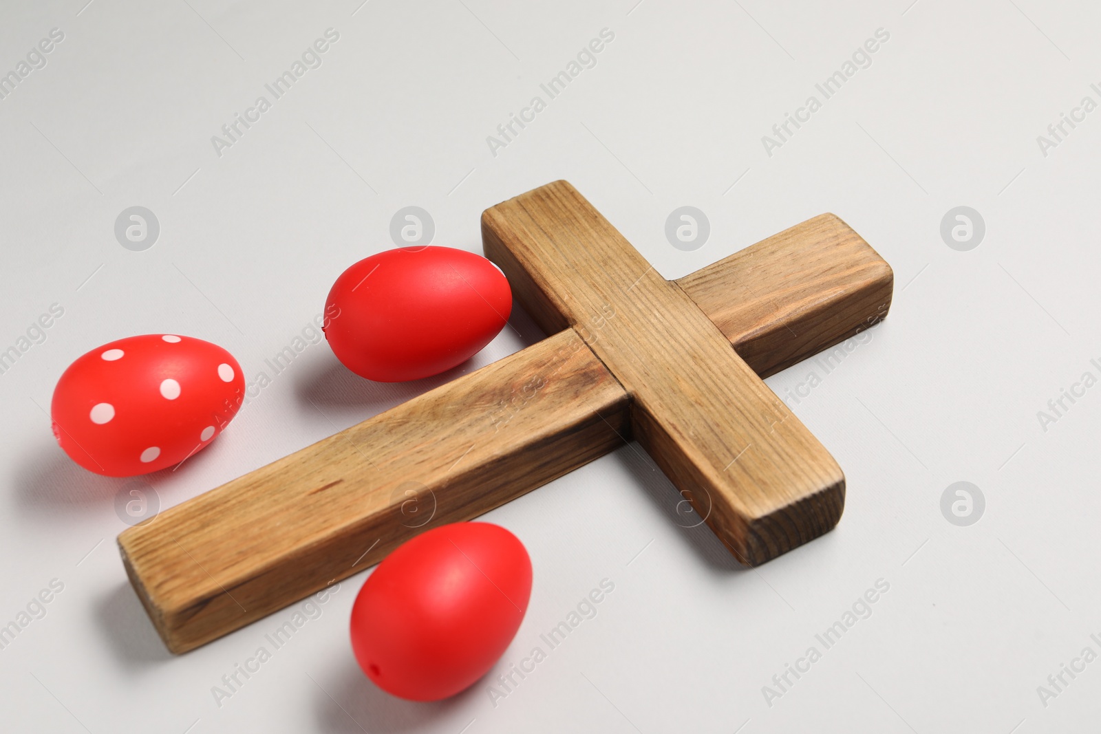 Photo of Wooden cross and painted Easter eggs on light grey background