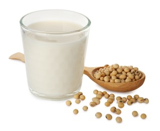 Glass of fresh soy milk and spoon with beans on white background