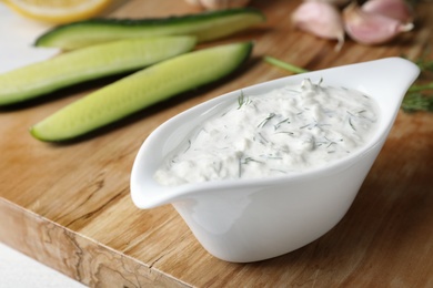 Photo of Cucumber sauce with ingredients on wooden board. Traditional Tzatziki