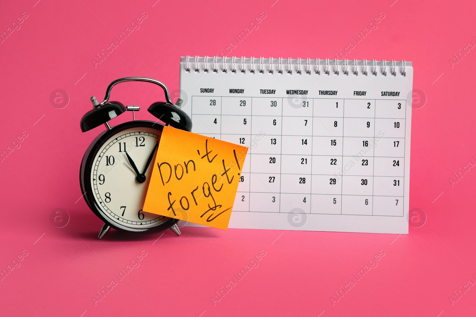 Photo of Alarm clock, calendar and reminder note with phrase Don't forget on pink background