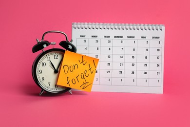 Alarm clock, calendar and reminder note with phrase Don't forget on pink background