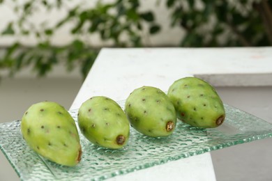 Delicious fresh ripe opuntia fruits on glass plate outdoors