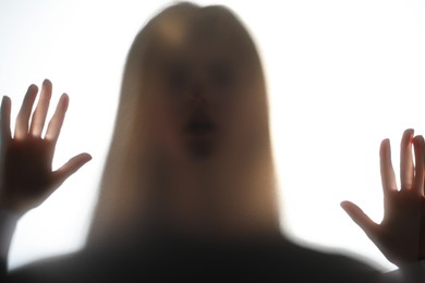 Photo of Silhouette of creepy ghost behind glass against white background