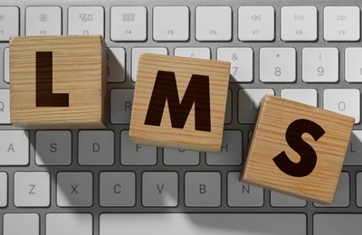 Learning management system. Wooden cubes with abbreviation LMS on computer keyboard, top view